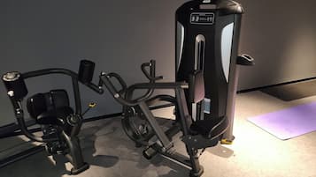 Une salle de sport équipée de matériel d’exercice, notamment une machine pour les exercices de développé couché et une machine pour les exercices de presse à cuisses.