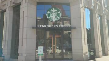 A Starbucks Coffee storefront with a glass entrance, a signboard, and a parking sign.