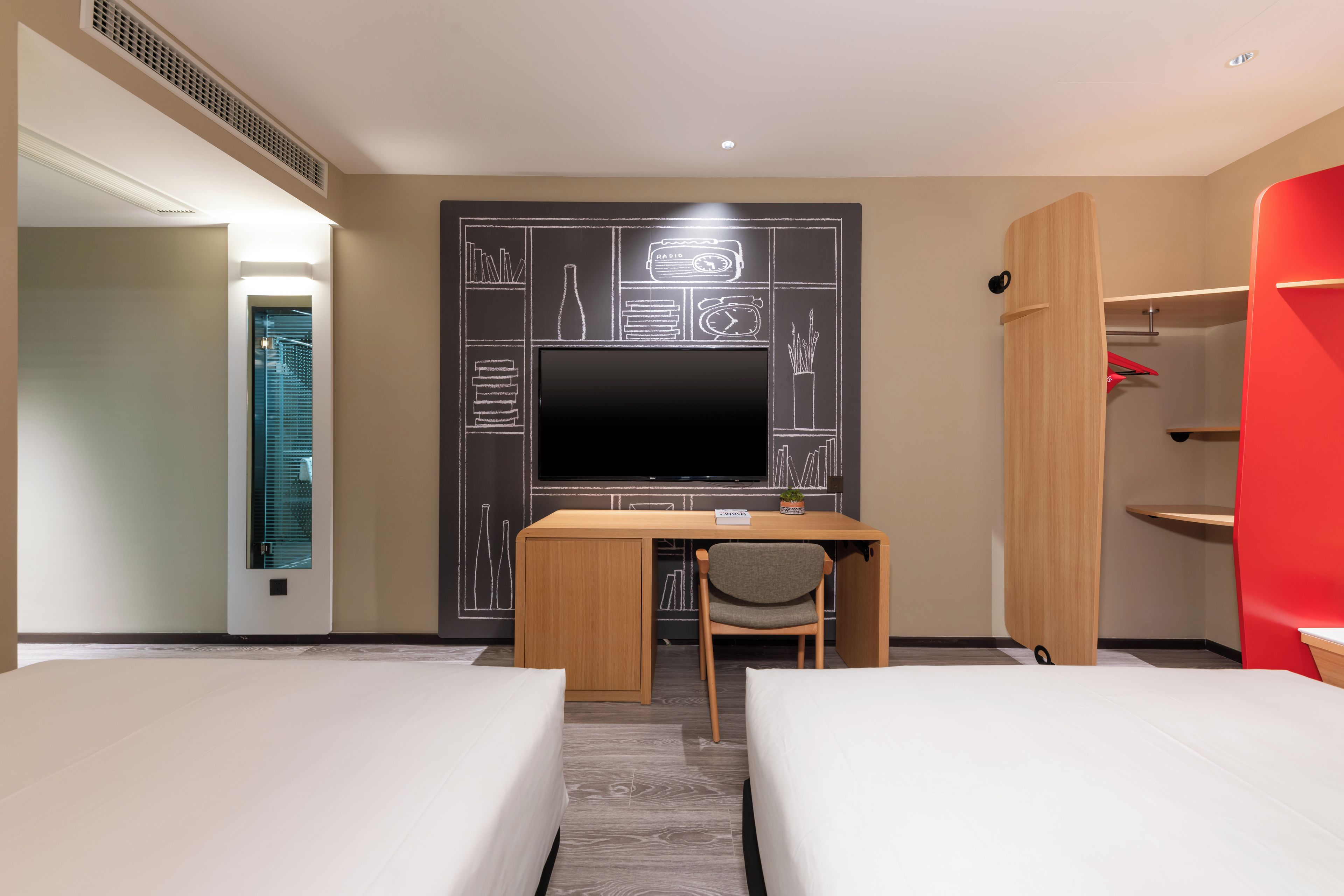 Een hotelkamer met een bed, een bureau met stoel, een televisie en een garderobe.