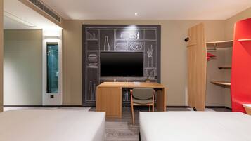 Een hotelkamer met een bed, een bureau met stoel, een televisie en een garderobe.