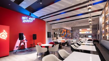 A modern interior with a red wall, white tables, and black chairs.