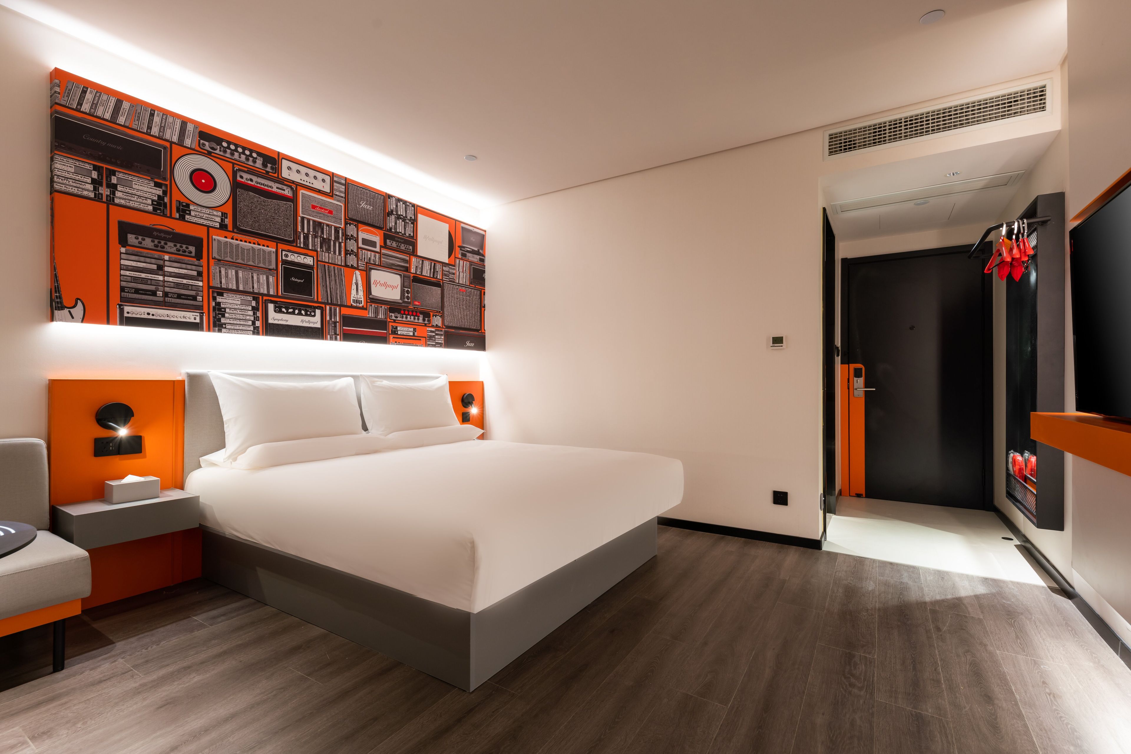 Quarto de hotel moderno com uma cama grande, televisão na parede e uma composição artística original.