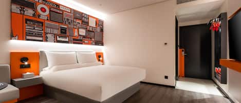 A modern hotel room with a large bed, a wall-mounted TV, and a unique wall art display.