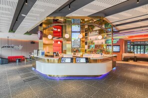 A modern bar area with a curved counter, digital menu displays, and seating.