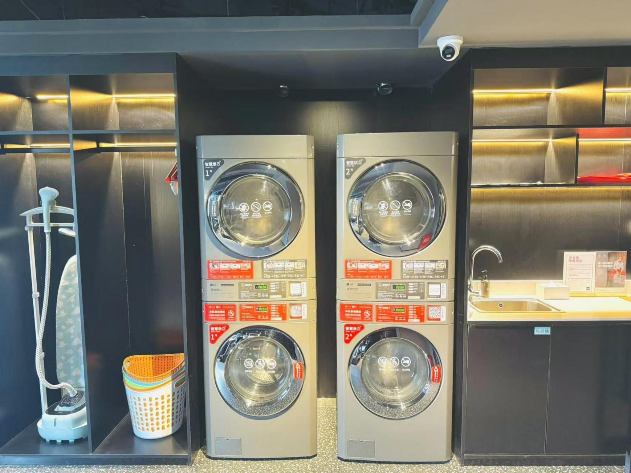 Een wasserette met twee wasmachines, een droogmachine en een wasbak.