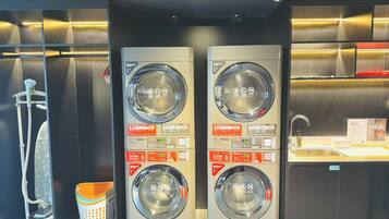 Een wasserette met twee wasmachines, een droogmachine en een wasbak.
