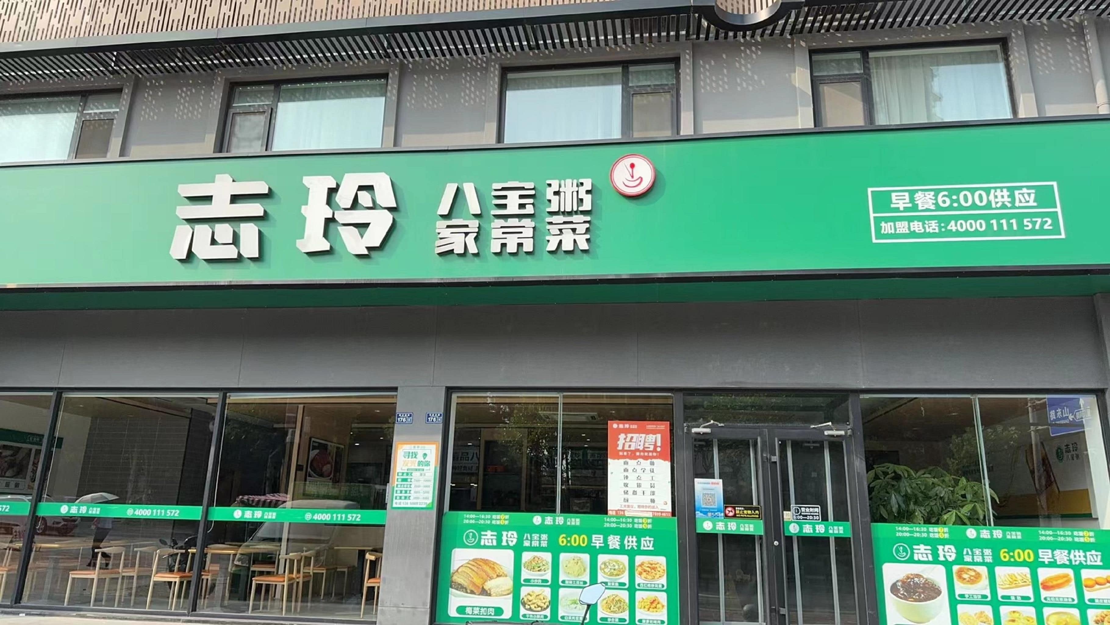 Een restaurant met een groen naambord waarop Chinese karakters en een telefoonnummer staan.