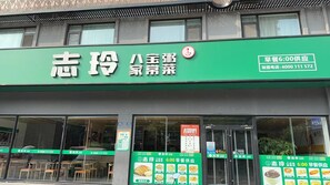 Un restaurant avec une enseigne verte sur laquelle figurent des caractères chinois et un numéro de téléphone.
