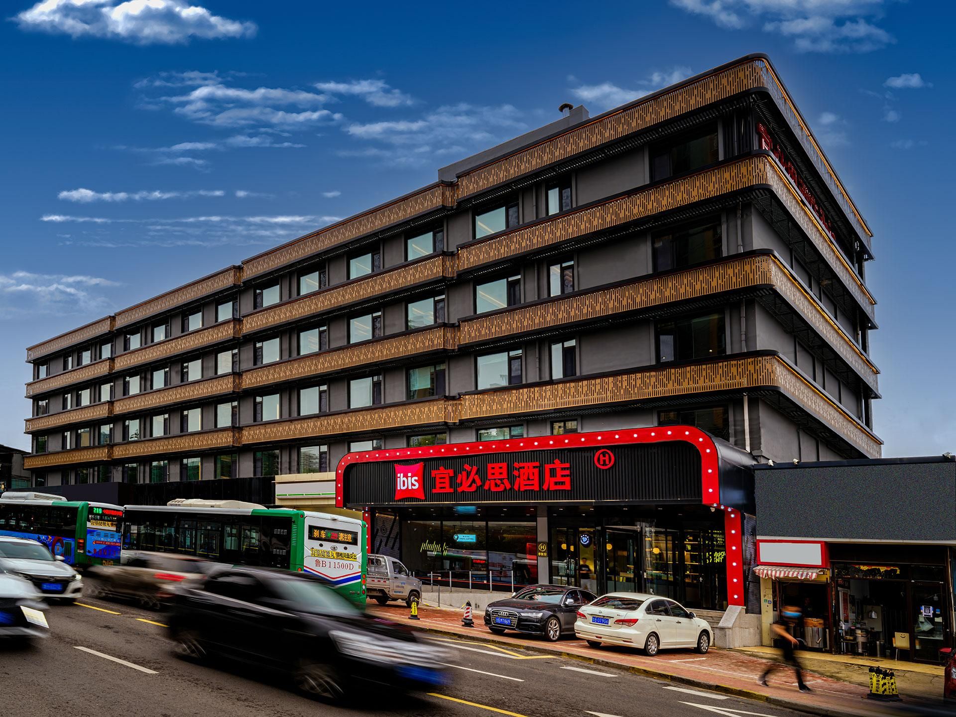 A multi-story building with a prominent red sign, a modern architectural design, and a busy street with vehicles.