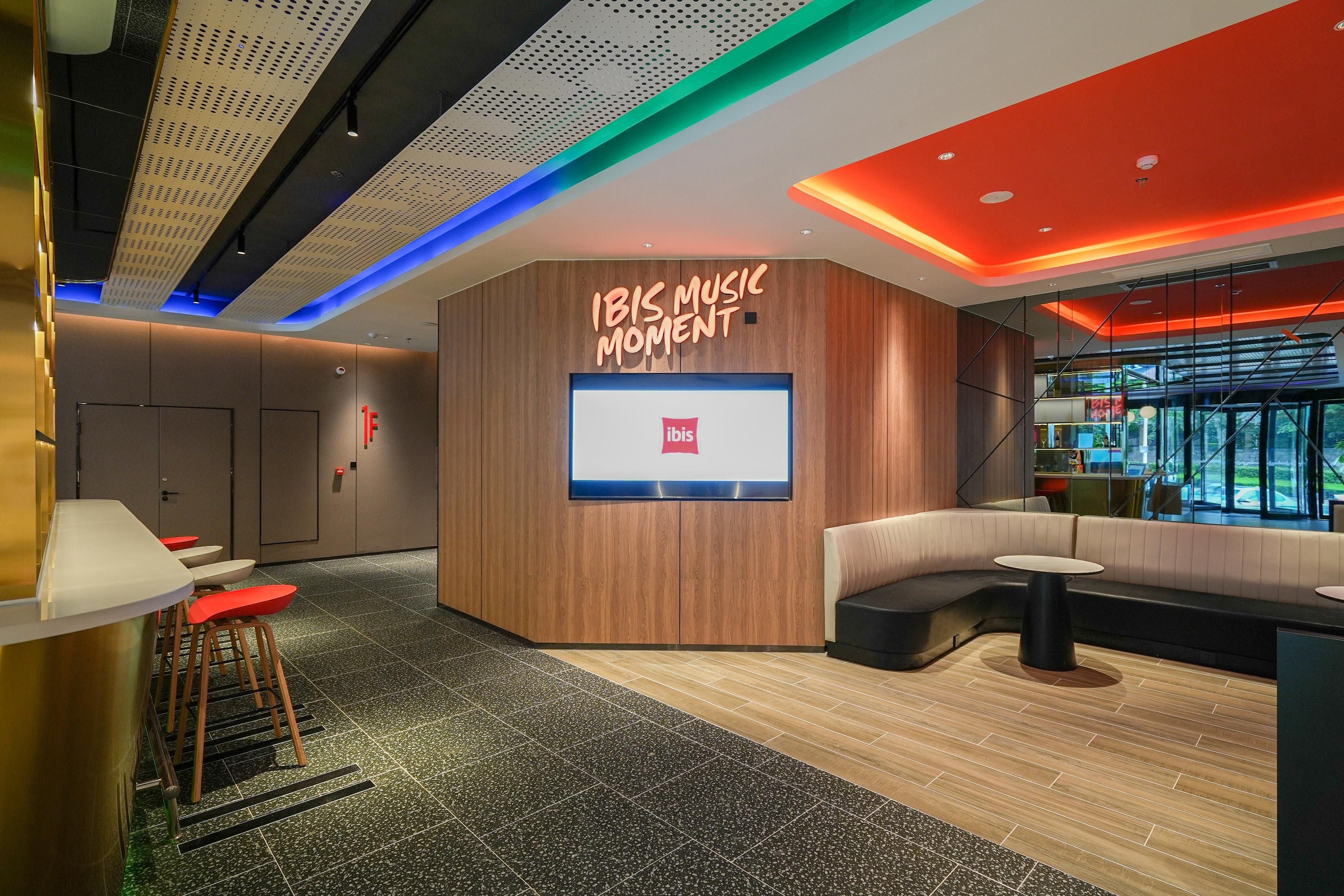 A modern lounge area with a wooden accent wall, a large screen, and seating arrangements.