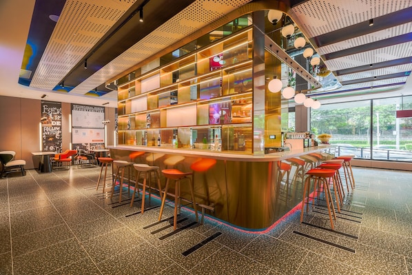 A modern bar area with stools, a counter, and a view of the outdoors. - Ibis Qingdao Xinduxin Capitamall Hotel (Qingdao)