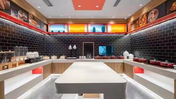 A modern kitchen with a central island, black tiled walls, and red accents.