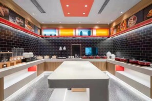 A modern kitchen with a central island, black tiled walls, and red accents. - Ibis Qingdao Xinduxin Capitamall Hotel (Qingdao)