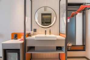 Un baño moderno con un espejo grande, un lavamanos y una zona de ducha.
