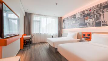 A hotel room with two beds, a TV, a desk, and a wall with musical equipment.