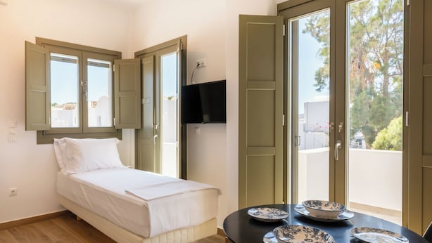 Ein Zimmer mit einem Bett, einem Tisch mit Tellern, einem Fernseher und einem Balkon mit Aussicht.
