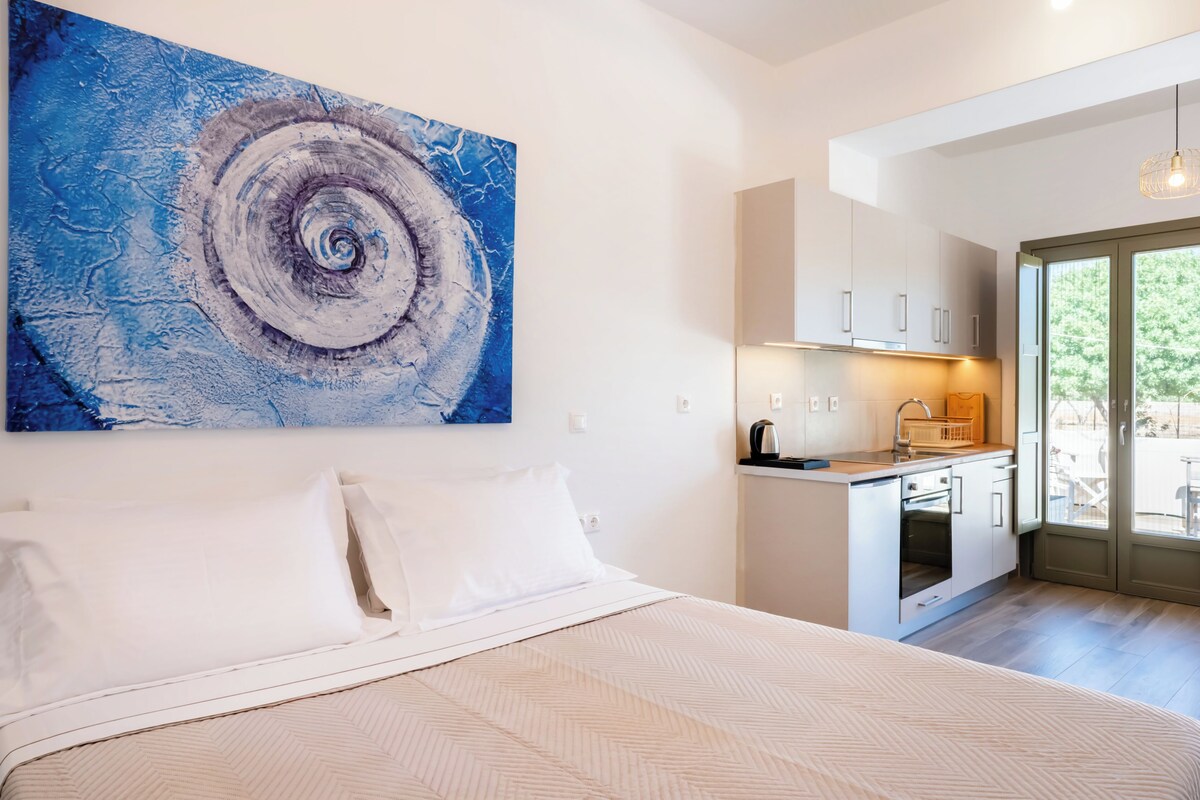 Ein Schlafzimmer mit Bett, einer Küchenzeile und einem großen abstrakten Gemälde an der Wand.