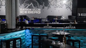 A bar area with a blue cushioned seating area, a bar counter with glasses and bottles, and a wall with a 'DANCE CLUB ICEBERG' sign. - Hotel Iceberg (Sofia)