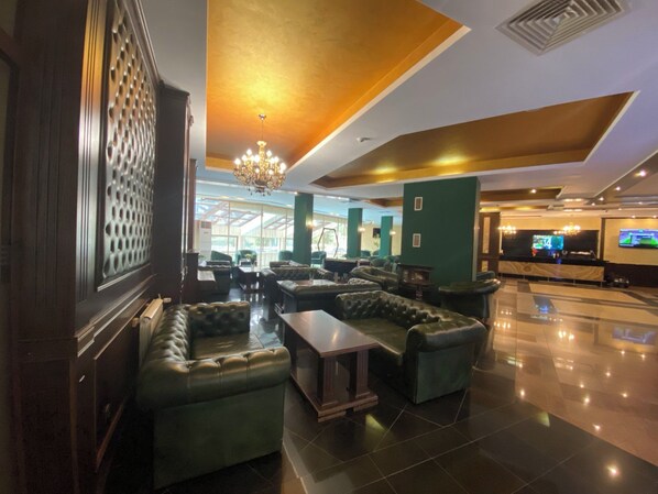 A lobby with leather sofas, a chandelier, a reception desk, and a large screen. - Hotel Iceberg (Sofia)