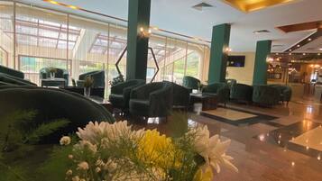 A spacious lobby with a high ceiling, large windows, and a central floral arrangement.