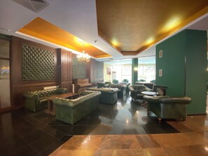 A lobby with leather seating, a chandelier, and a green accent wall. - Hotel Iceberg (Sofia)