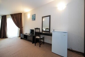 A room with a bed, a desk with a chair, a television, and a refrigerator. - Hotel Iceberg (Sofia)