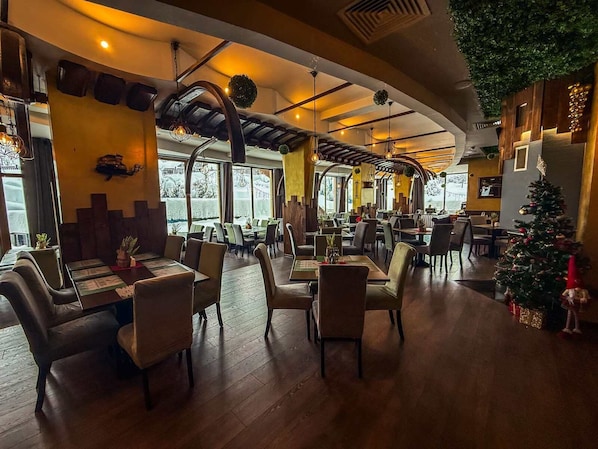 A restaurant with wooden flooring, high ceilings, and a Christmas tree.