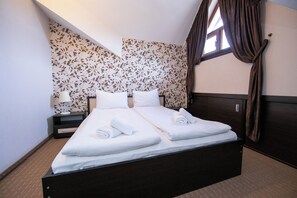 A double bed with white linens, a nightstand with a lamp, and a window with curtains. - Hotel Iceberg (Sofia)