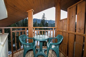 A wooden deck with a table and chairs, overlooking a snowy mountain landscape. - Hotel Iceberg (Sofia)