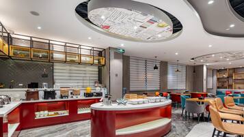 Een modern restaurant met een centraal rode toonbank, een zitgedeelte en een plafond met een cirkelvormig ontwerp.