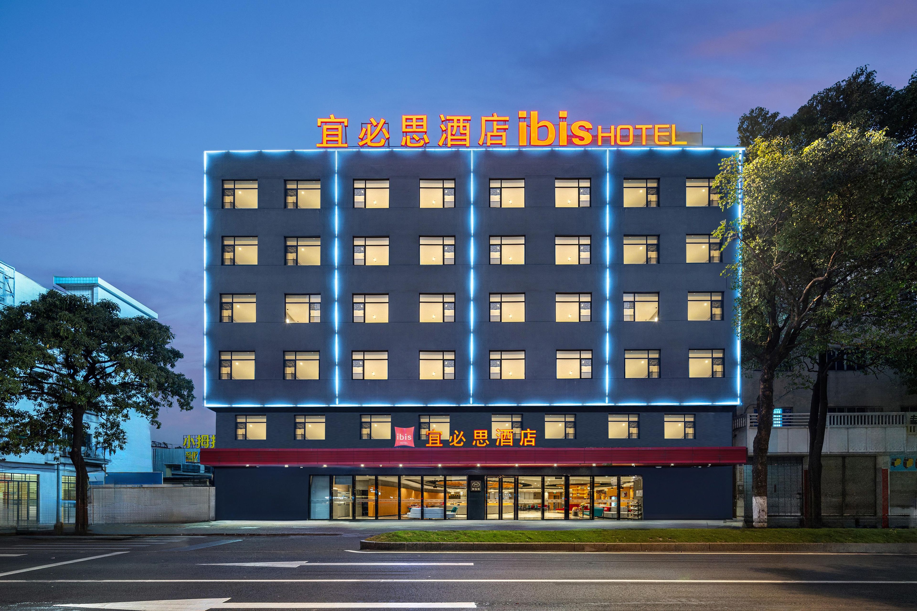 Un hotel de varios pisos con fachada moderna, señalización iluminada y entrada a nivel de calle.