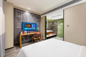 A hotel room with a bed, a desk with a computer, a chair, a television, and a bathroom with a mirror and towel rack. - Ibis Hotel Foshan Shunde Jing Long Subway Station (Foshan)