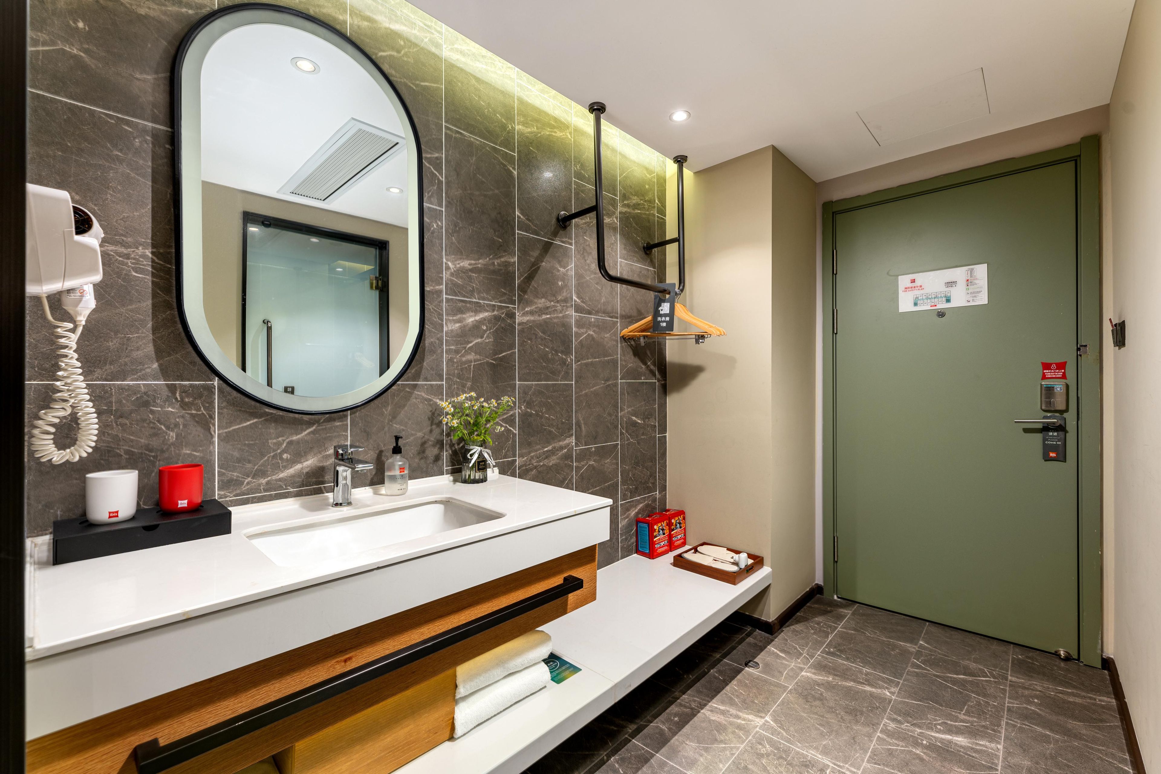 Uma casa de banho moderna com um espelho grande, um secador de cabelo, uma pia e um porta-toalhas.