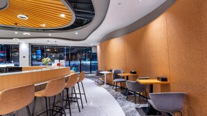 Ein modernes Interieur mit gewölbter Holzbalkendecke, Barbereich und Sitzgelegenheiten.