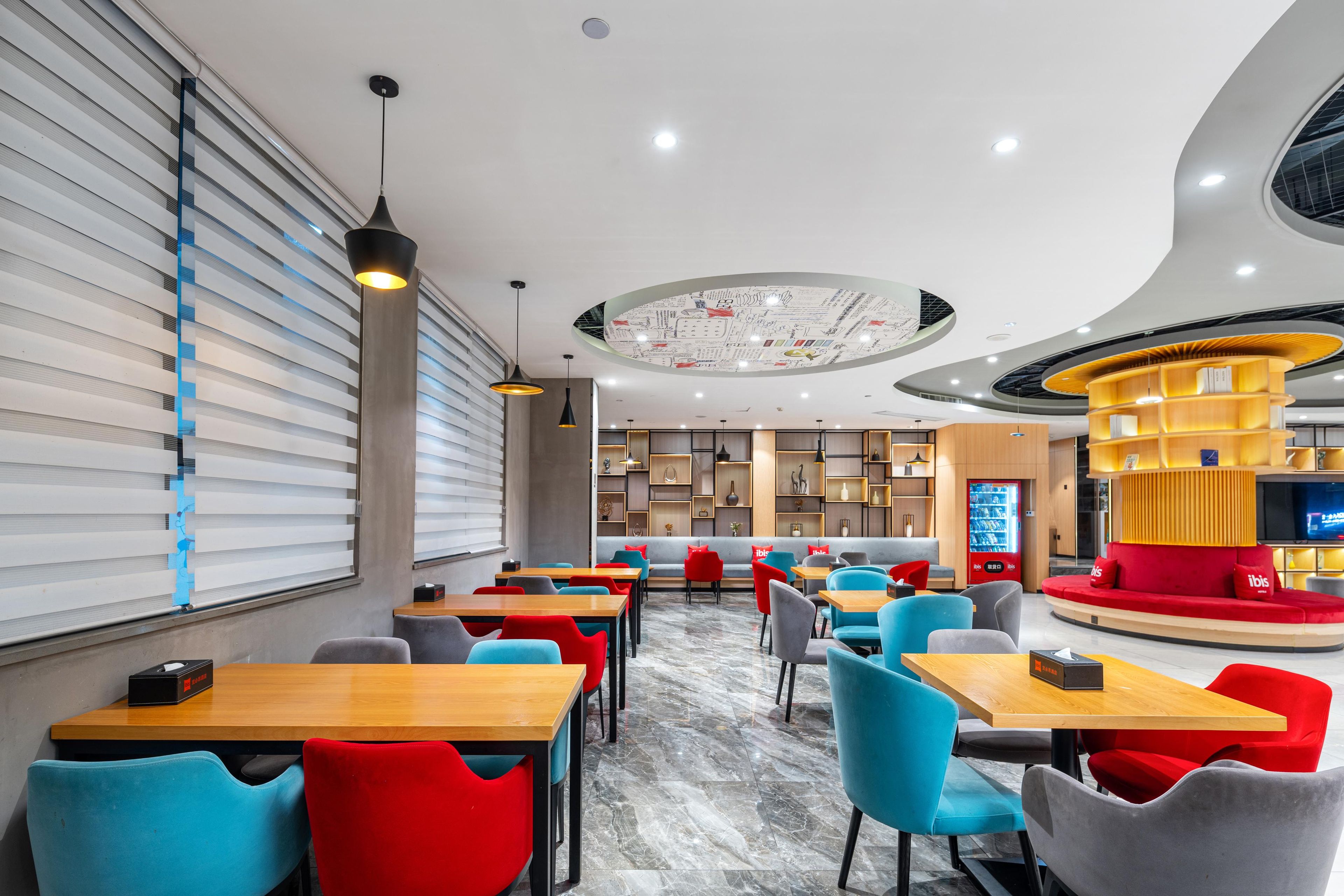 A modern restaurant with a central seating area, individual tables, and a distinctive circular ceiling design.
