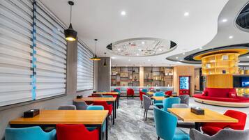 A modern restaurant with a central seating area, individual tables, and a distinctive circular ceiling design.
