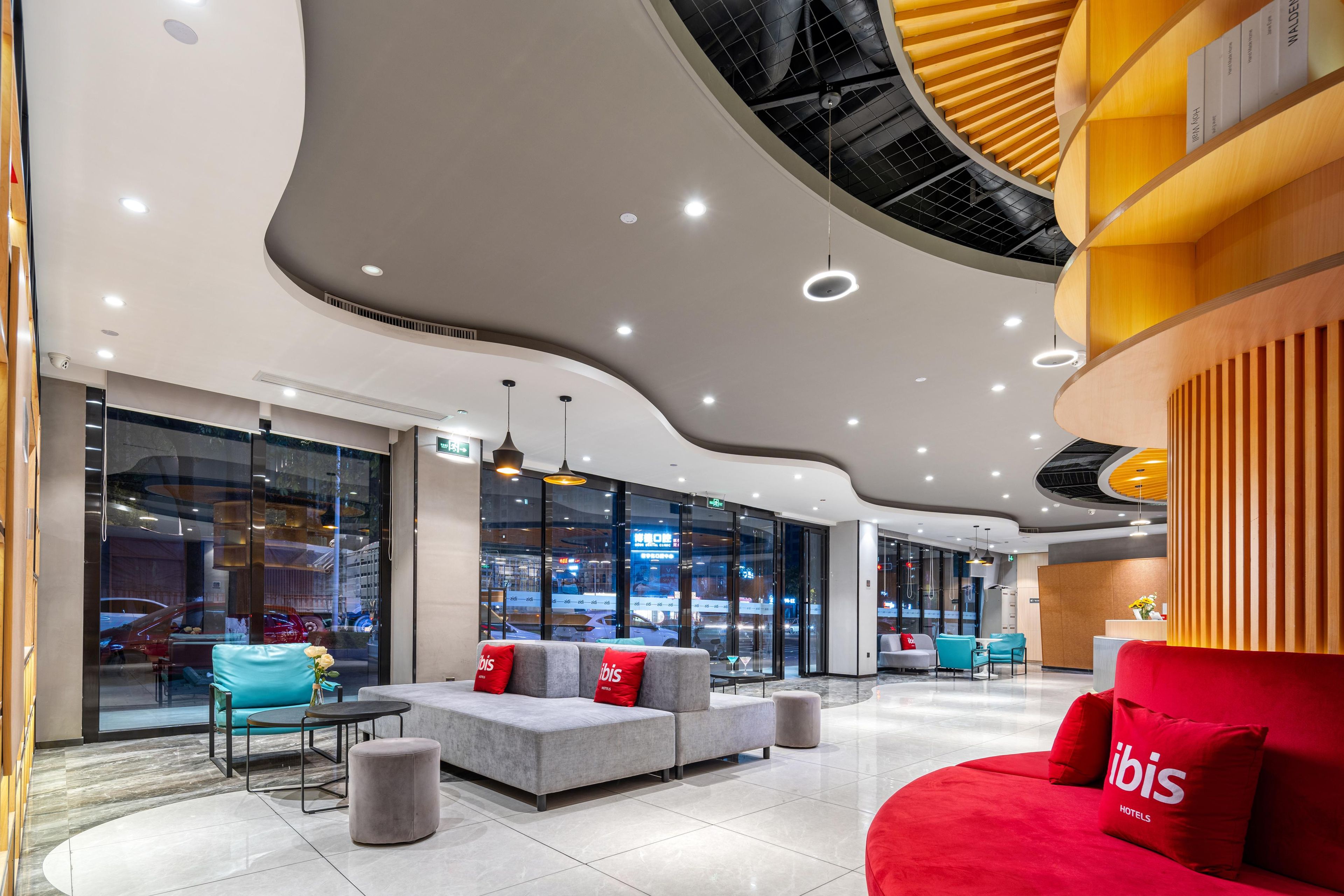 Een moderne hotellobby met zithoeken, een receptiebalie en grote ramen met uitzicht op de omgeving.