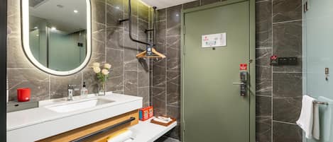 A modern bathroom with a large mirror, a sink, a towel rack, and a shower area.