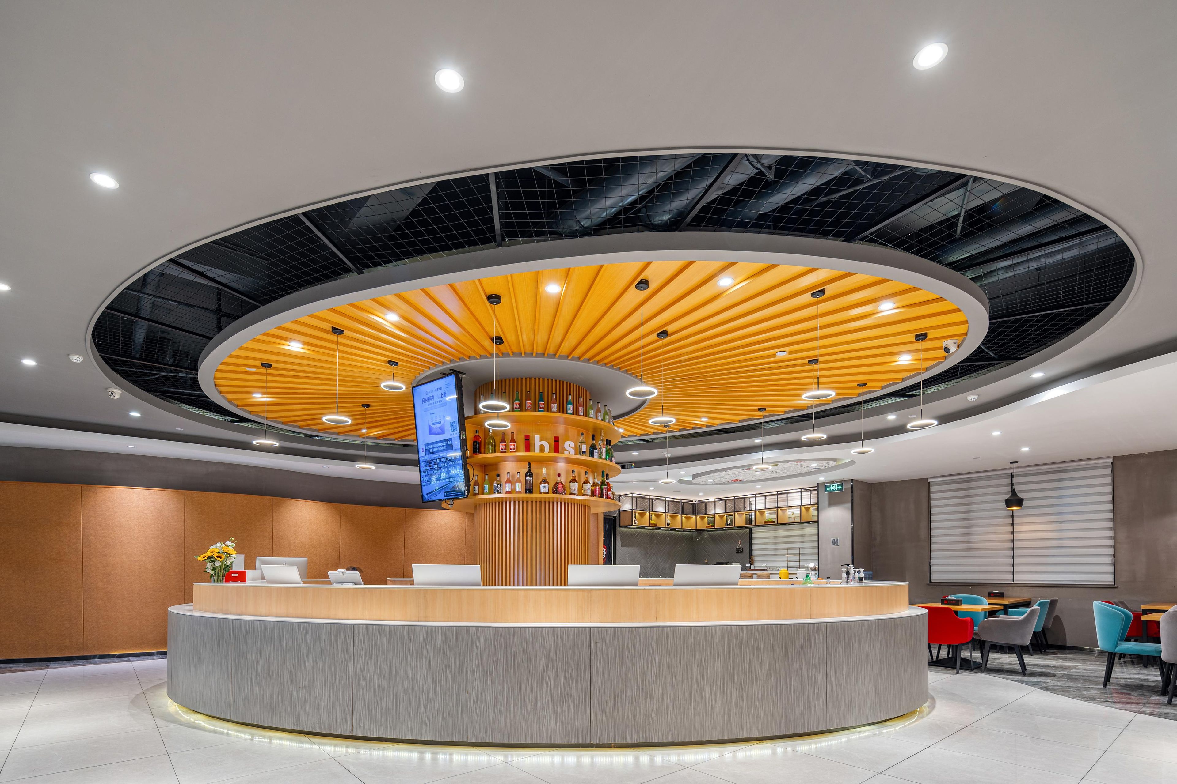 A modern reception area with a central counter, a digital screen, and a circular ceiling design.