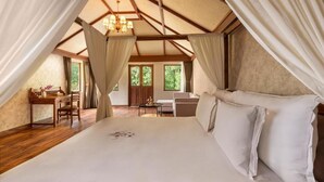 Un dormitorio con una cama grande, un escritorio, una silla, cortinas y una araña.