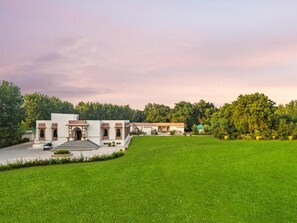 A building with a large lawn in front, a driveway, and a vehicle parked near the entrance. - Zana Forest Resort Ranthambore (Sawai Madhopur)