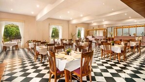 Un comedor con piso a cuadros, mesas redondas y sillas de madera.