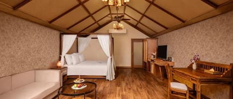 A cozy room with a bed, a sofa, a dining table, and a TV.
