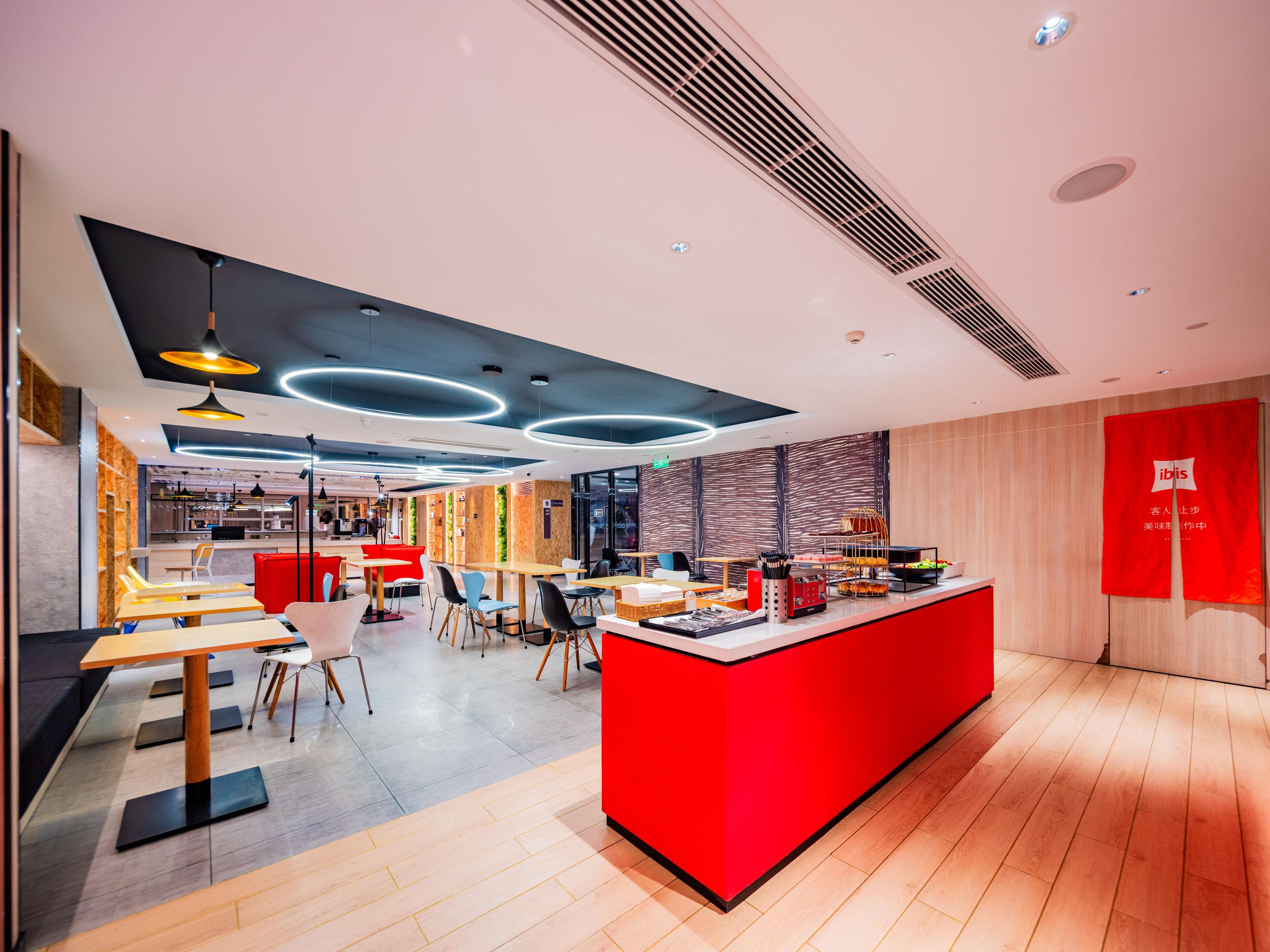 Un restaurante moderno con una barra roja, suelo de madera e iluminación contemporánea.