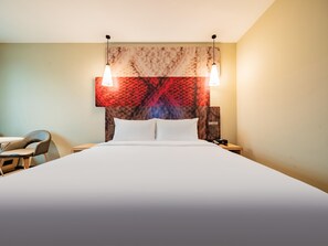 Een hotelkamer met een bed, twee nachtkastjes, een stoel en een hoofdbord met een patroon.
