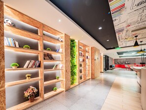 A modern interior with wooden bookshelves, a green vertical garden, and a red reception desk. - Ibis Chengdu Kuanzhai Alley Center Hotel (Chengdu)