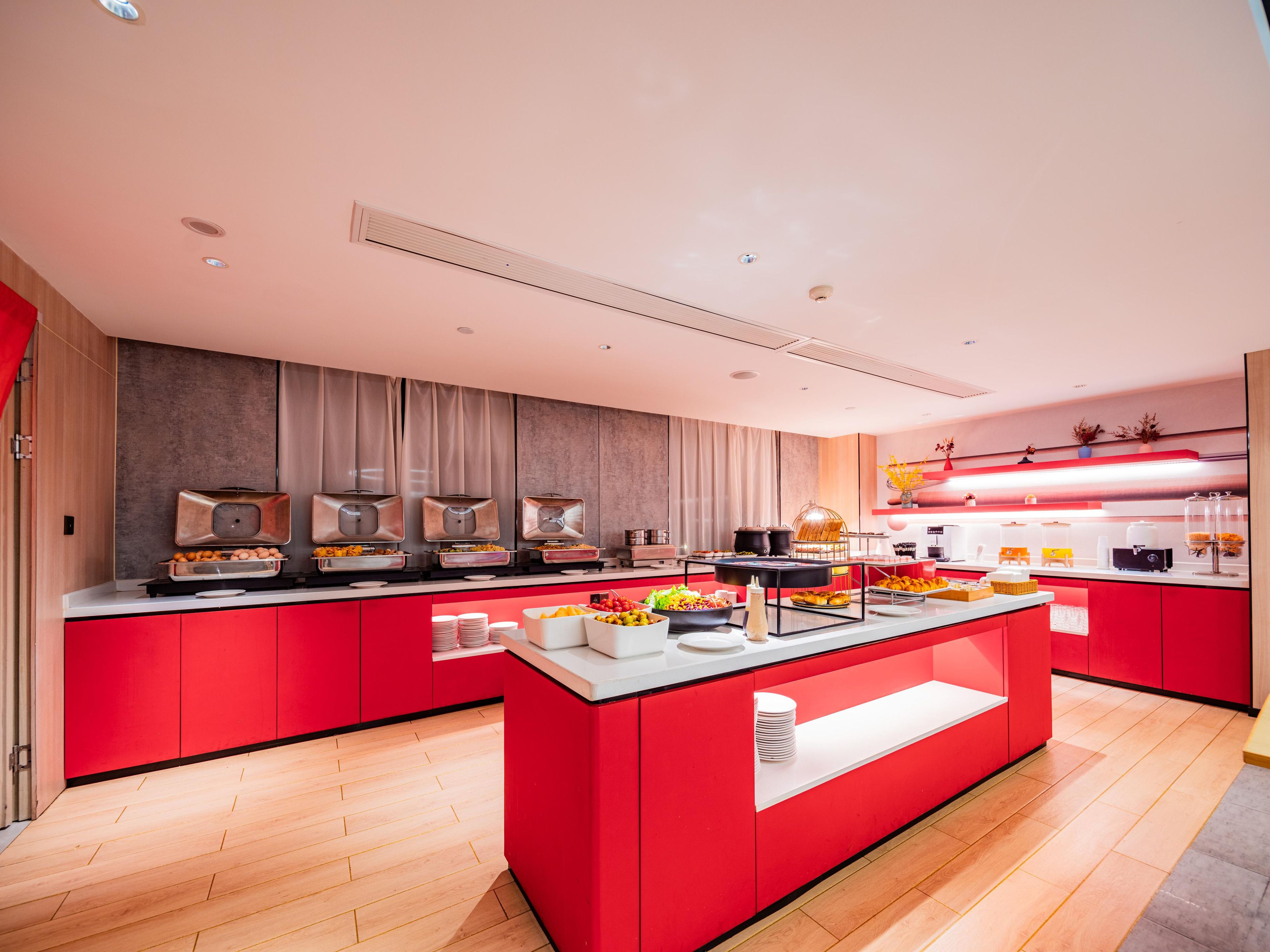 Una cocina moderna con armarios rojos, una isla central y diferentes puestos de comida.