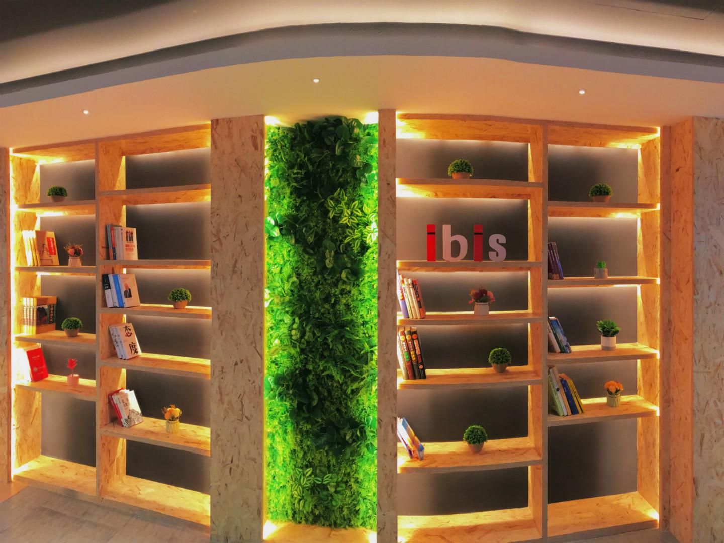 Una biblioteca moderna con estanterías de madera y un jardín vertical verde.