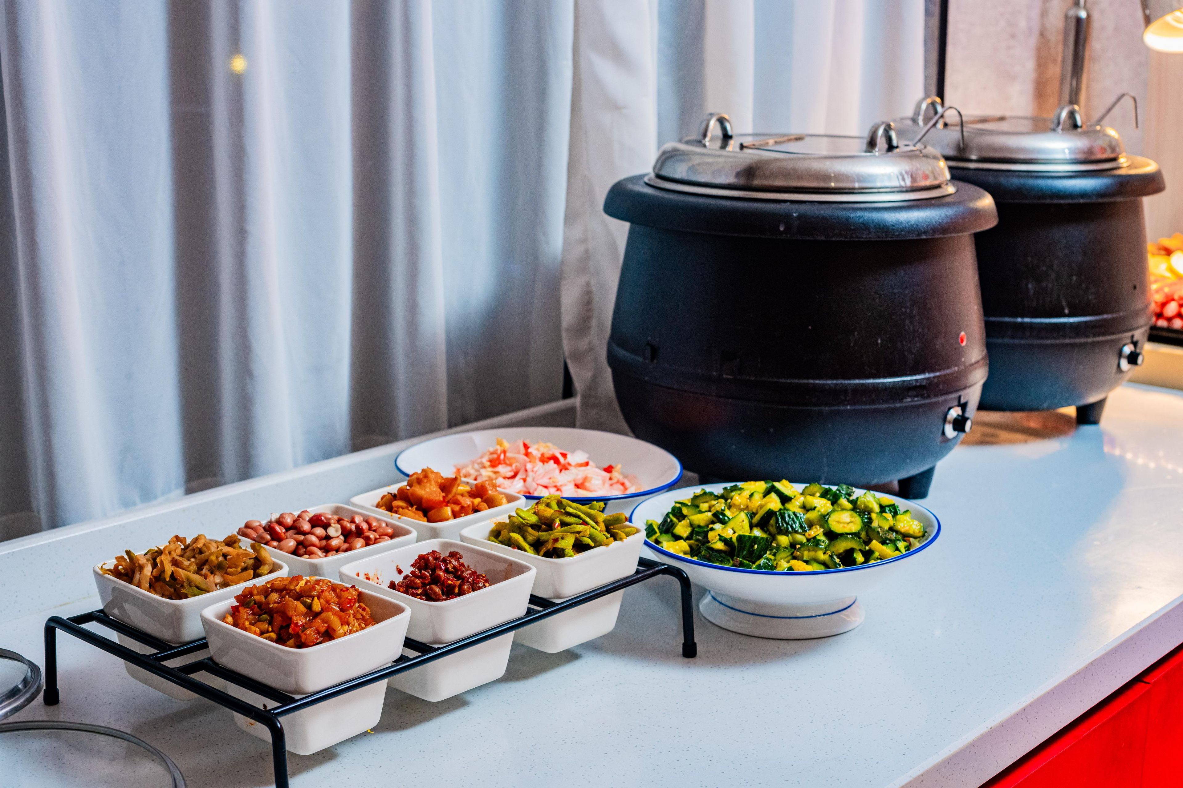 A buffet table with various dishes and two large pots.
