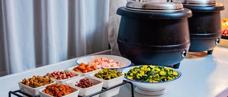 A buffet table with various dishes and two large pots.
